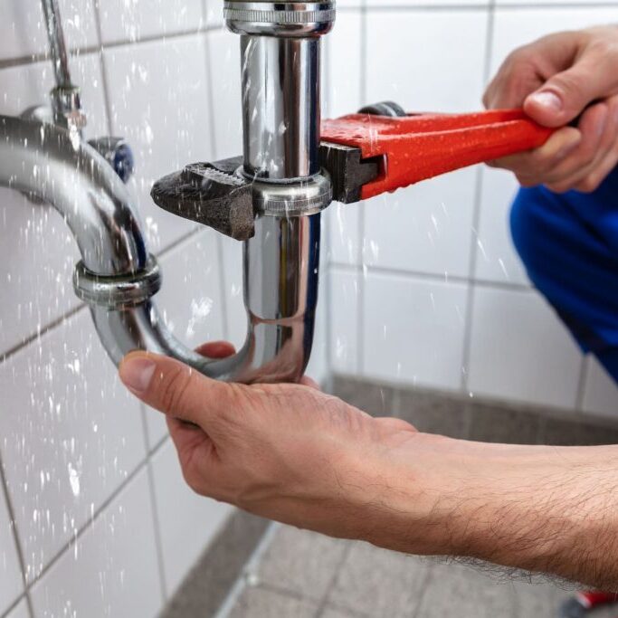 plumber adjusting drain with wrench
