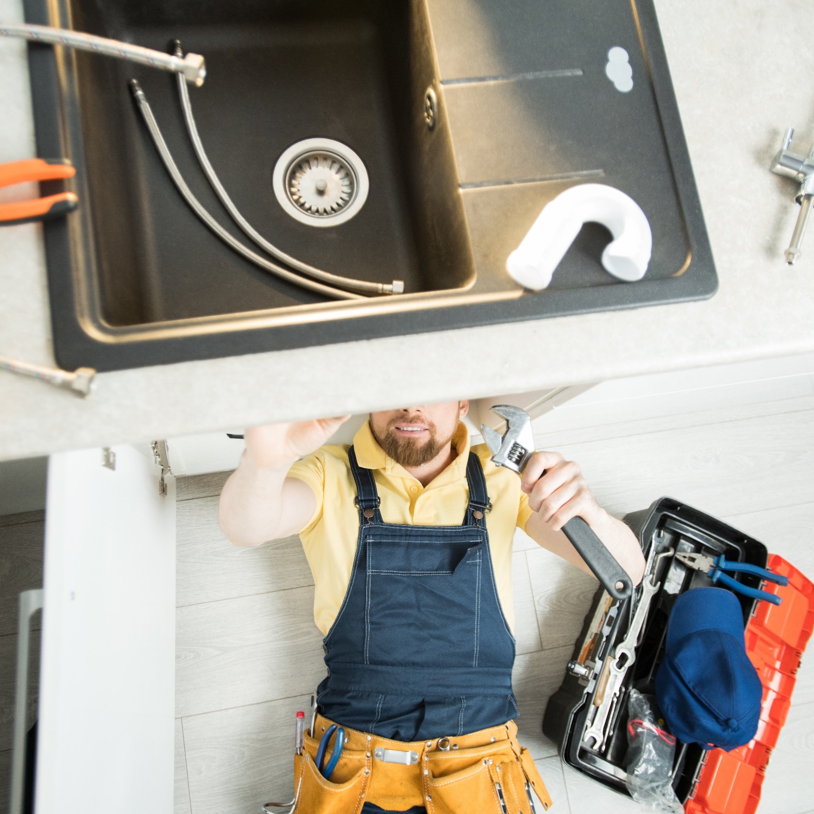 plumber under a sink fixing the drain pipe