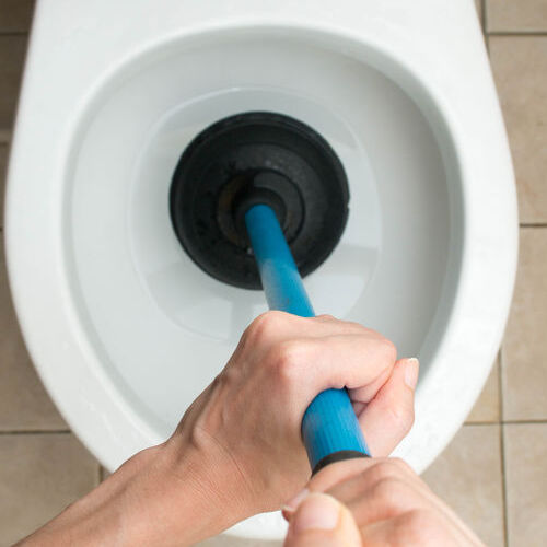 An Emergency Plumber Unclogs a Toilet.